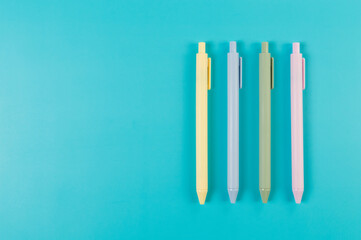 Top view of colorful pens on blue background. School, office wallpaper. Flat lay, copy space.