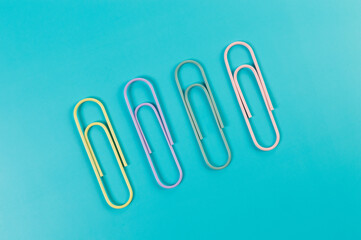 Top view of colorful paperclips on blue background. School, office wallpaper. Flat lay, copy space.