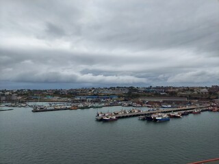 Fototapeta premium Port Elizabeth South Africa apr 6 2024 Cloudy Day Over Bustling Harbor and Docked Boats
