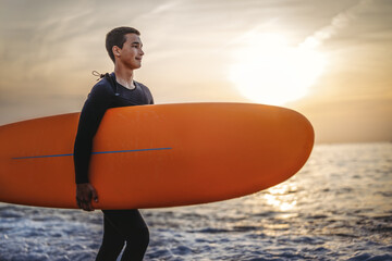 Happy young fit man with surfing board at beach, sea and ocean for summer holiday, travel adventure