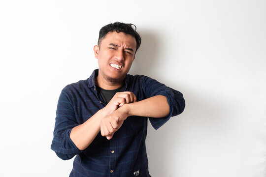 Adult Asian man scratching his hand and showing uncomfortable expression