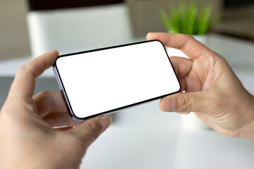 male hands holding phone horizontally with isolated screen cafe table