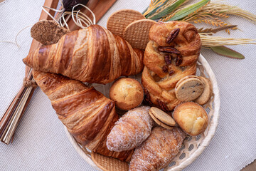 Sweet bakery products and croissant in the basket captured from above (top view), white background