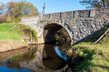 Fototapeta premium autumn landscape with a stone arched bridge over Vizla near Vidagas, Vidagas village, Latvia