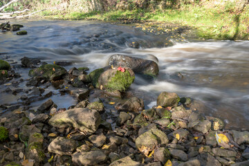 fast river between stones, stream of water passes the stone, ecology in the river, beautiful natural environment as background, blurred stream of water