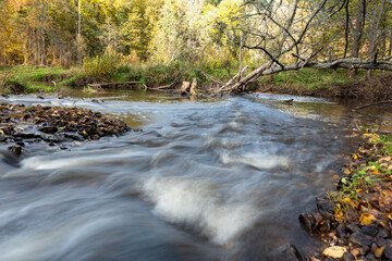 fast river between stones, stream of water passes the stone, ecology in the river, beautiful natural environment as background, blurred stream of water