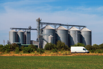 White van passing by agricultural farm silos for grain storage © Bits and Splits