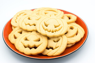 Plate with Halloween pumpkin-shaped cookies on a white background.