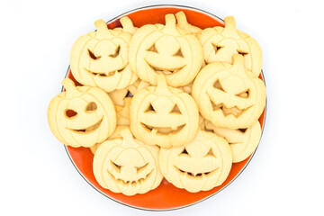 Top view of a plate with Halloween pumpkin-shaped cookies on a white background.