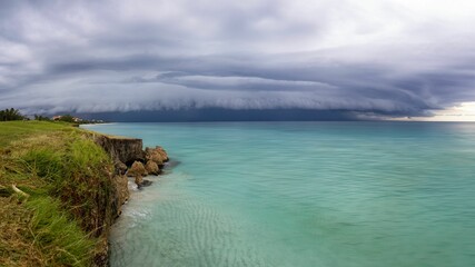 Dramatic storm clouds over turquoise ocean.