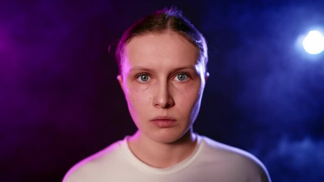 Frustrated you woman looking at camera, moving arms slowly, portrait in studio. Moving back shot from closeup view of face to medium portrait, emotions and feelings, amazing dreams in purple light