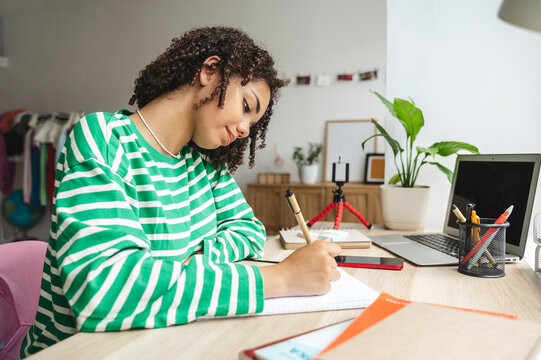 Smiling teenage girl studying at desk in bedroom