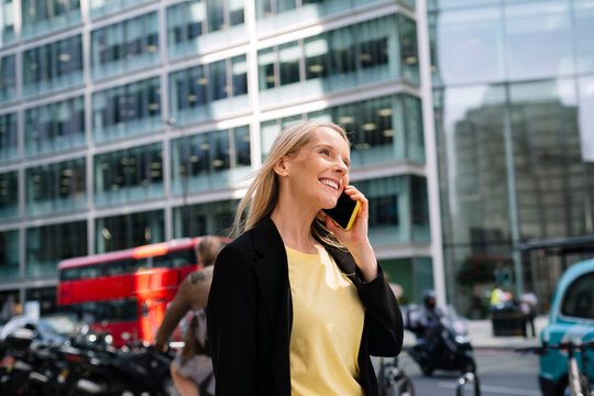 Happy businesswoman talking on smart phone at street - Powered by Adobe