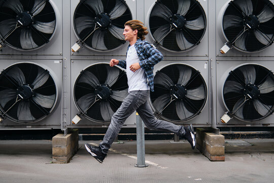 Young man running in front of heat pumps