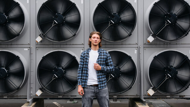 Confident young man standing in front of heat pumps