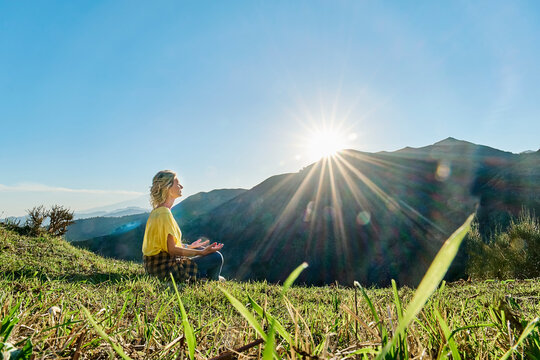 Woman meditating in front of mount Etna on sunny day, Italy - Powered by Adobe