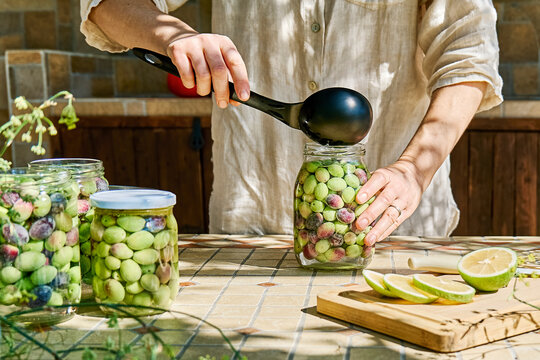 Mature woman preparing fermented olives in glass jar