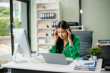 Frustrated young businesswoman working on a laptop computer sitting at his working place