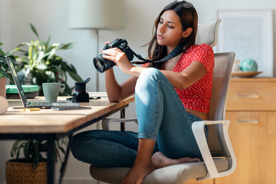 Photographer checking photographs on camera at desk in home office