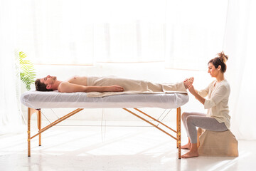 Physical therapist giving foot massage to man in spa