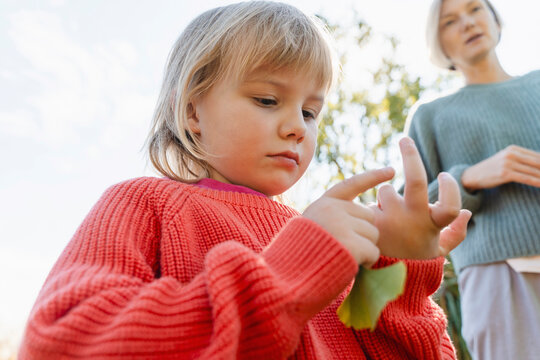 Cute blond girl in cardigan sweater counting on finger