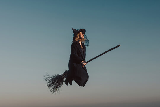 Woman wearing witch costume and flying in sky at Halloween