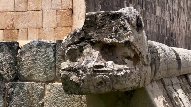 Handheld close-up panning shot of a stone serpent carving at the Great Ball Court in Chichen Itza, Mexico. 4K
