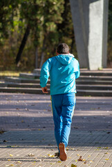 A man in a blue jacket and blue pants is walking down a sidewalk