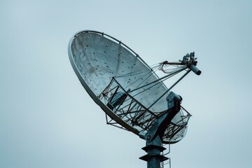 Large satellite dish antenna is pointing up to a cloudy sky, searching for a signal