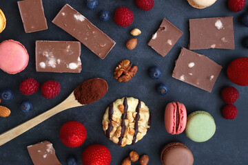 Macarons, chocolate, cookies, berries and various nuts on dark blue background. Top view.
