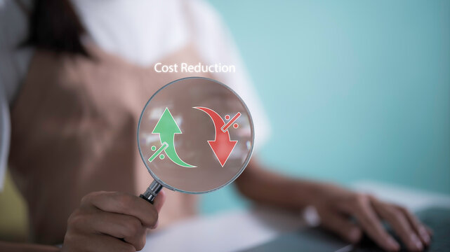Woman holding Magnifying glass with cost icon virtual screen, symbolizing the concept of cost reduction in business finance. cost optimization, achieving economic saving and financial efficiency