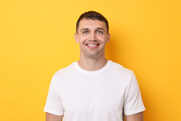 Fototapeta premium Smiling man with dental braces on yellow background