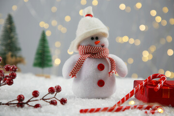 Cute decorative snowman and other Christmas decor on artificial snow, closeup