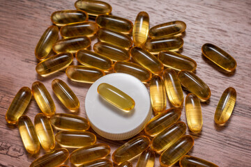A bottle cap of fish oil pills is on a wooden table