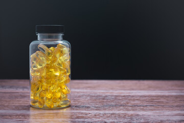 A bottle of yellow pills sits on a wooden table