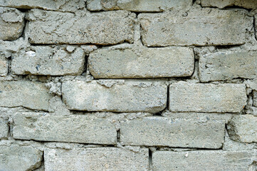 A weathered gray brick wall with some missing mortar.