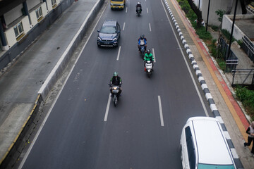An overhead view of a street in Jakarta, Indonesia, shows several motorbikes, a black car, and a...