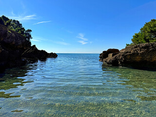 Sea bay on pebble beach among rocks.