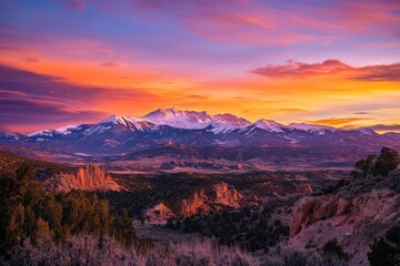 Fototapeta premium A stunning view of snow-capped mountains under a vibrant, multicolored twilight sky, capturing the essence of serene nature and vivid hues in this breathtaking landscape.