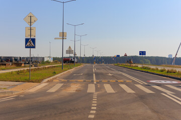 Wide road, highway, sun and blue sky on a summer day.
