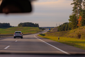 Wide road, highway, sun and blue sky on a summer day.