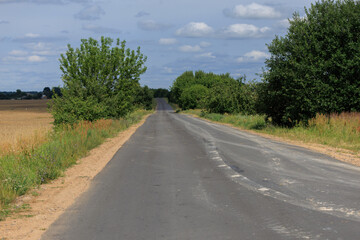 Wide road, highway, sun and blue sky on a summer day.
