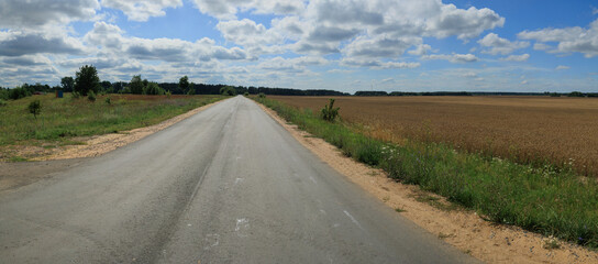 Fototapeta premium Wide road, highway, sun and blue sky on a summer day.