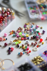 Colorful beads, letter beads, threads and other jewelry making supplies on white background. Making friendship bracelets concept. Selective focus.