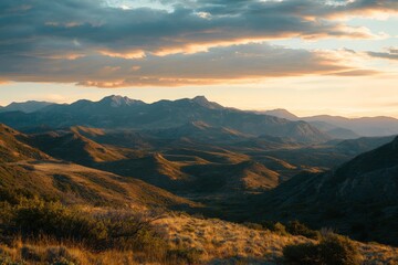 A picturesque view of rolling hills during the golden hour, with the last rays of the sun casting a warm glow over distant mountains, creating a serene setting.