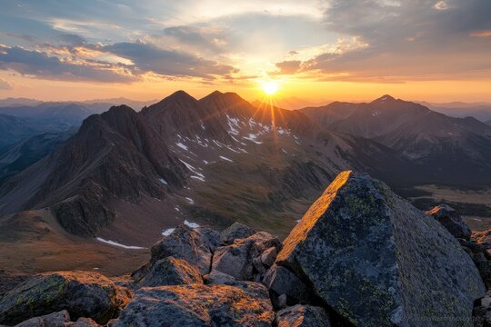 A majestic view of a mountain range during sunset, with the sun casting a golden glow over the rugged peaks and rocky terrain, instilling awe and wonder.