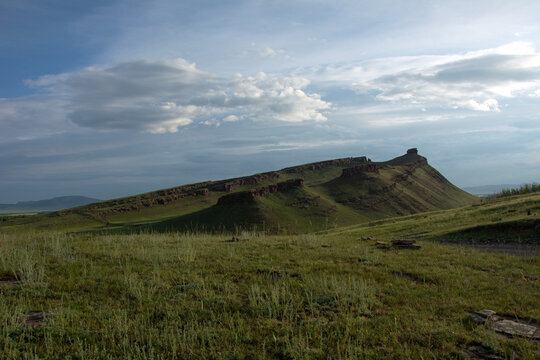 Natural background of rolling hills, green meadows and blue sky with clouds