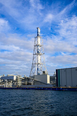 港の近くの近代的な発電所と高い煙突と青い空、雲