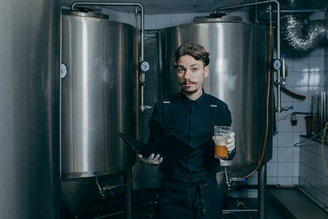 Young men inspecting quality of beer in brewery