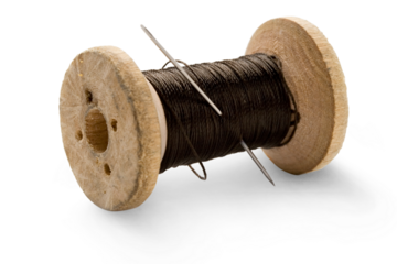 Thread bobbin and needle on white background